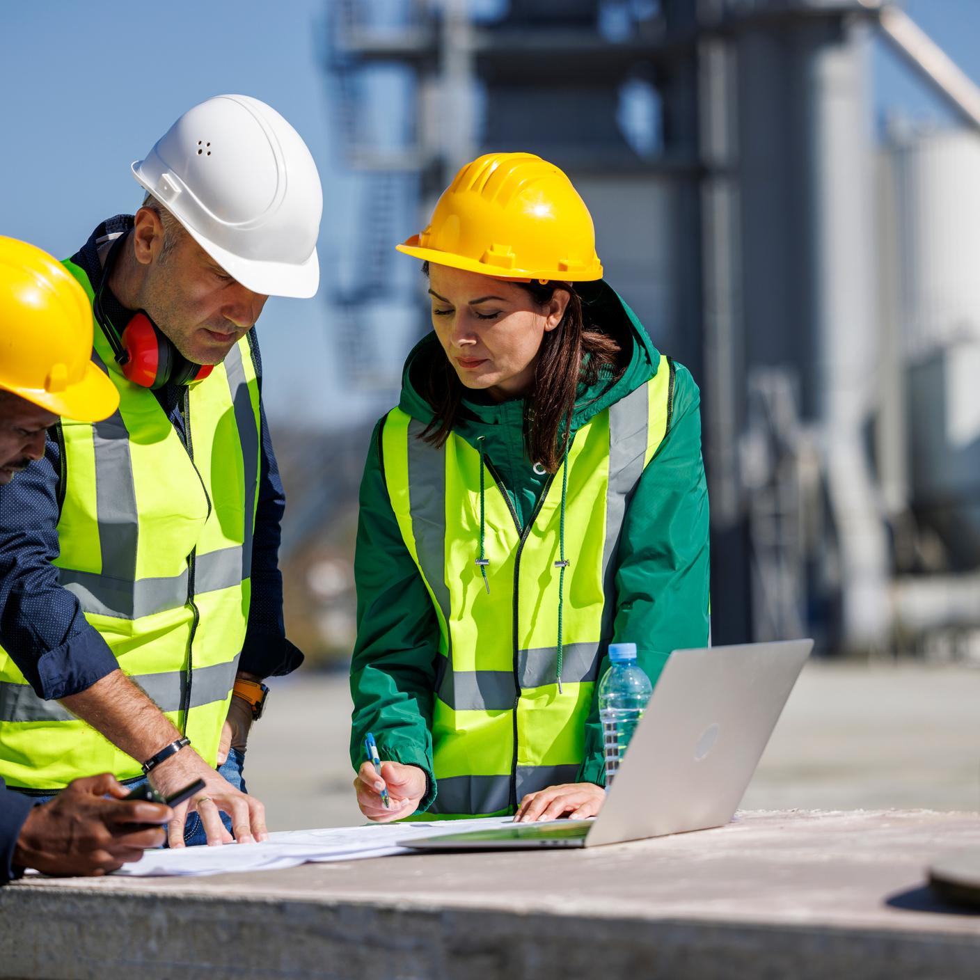 Engineers in safety attire discussing at an industrial facility