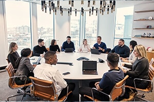 Many people in an office meeting room, sitting around a large table