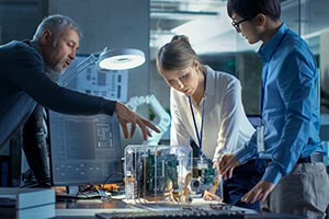 Three people working together on a project in front of a desk