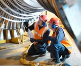 Workers kneeling inspecting the quality of a metal construction