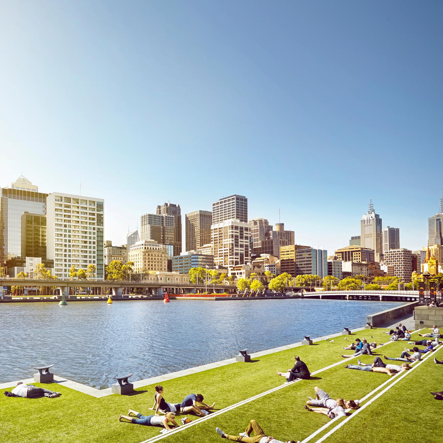 People sitting in the sun on grass in a modern park