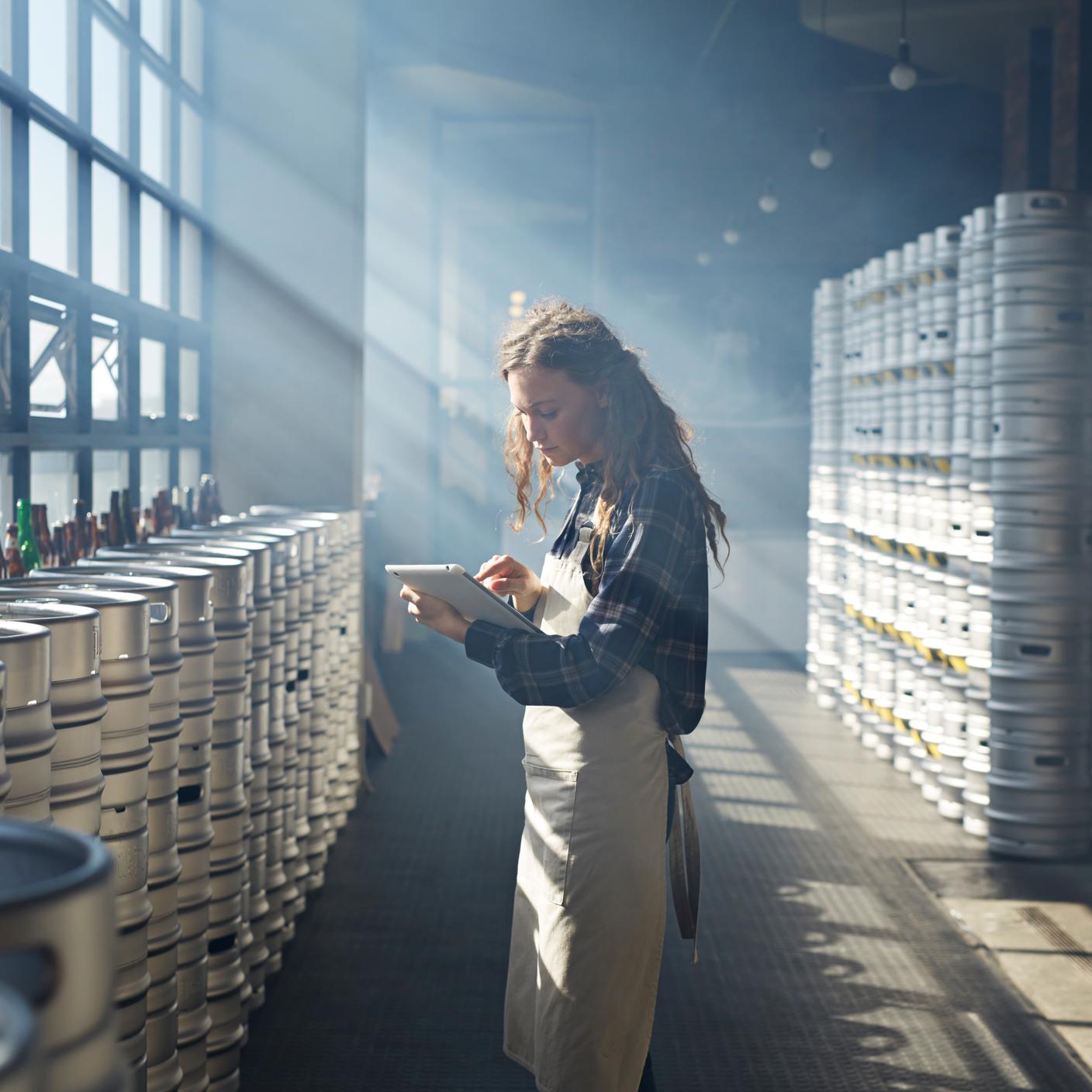 A woman looking at her screen while standing in her warehouse