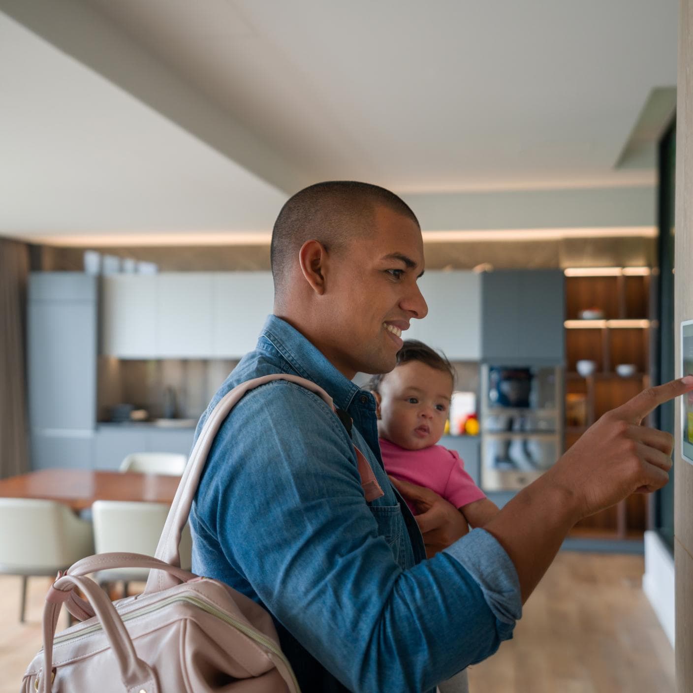 Happy man leaving the house with his baby and locking the door using a home automation system