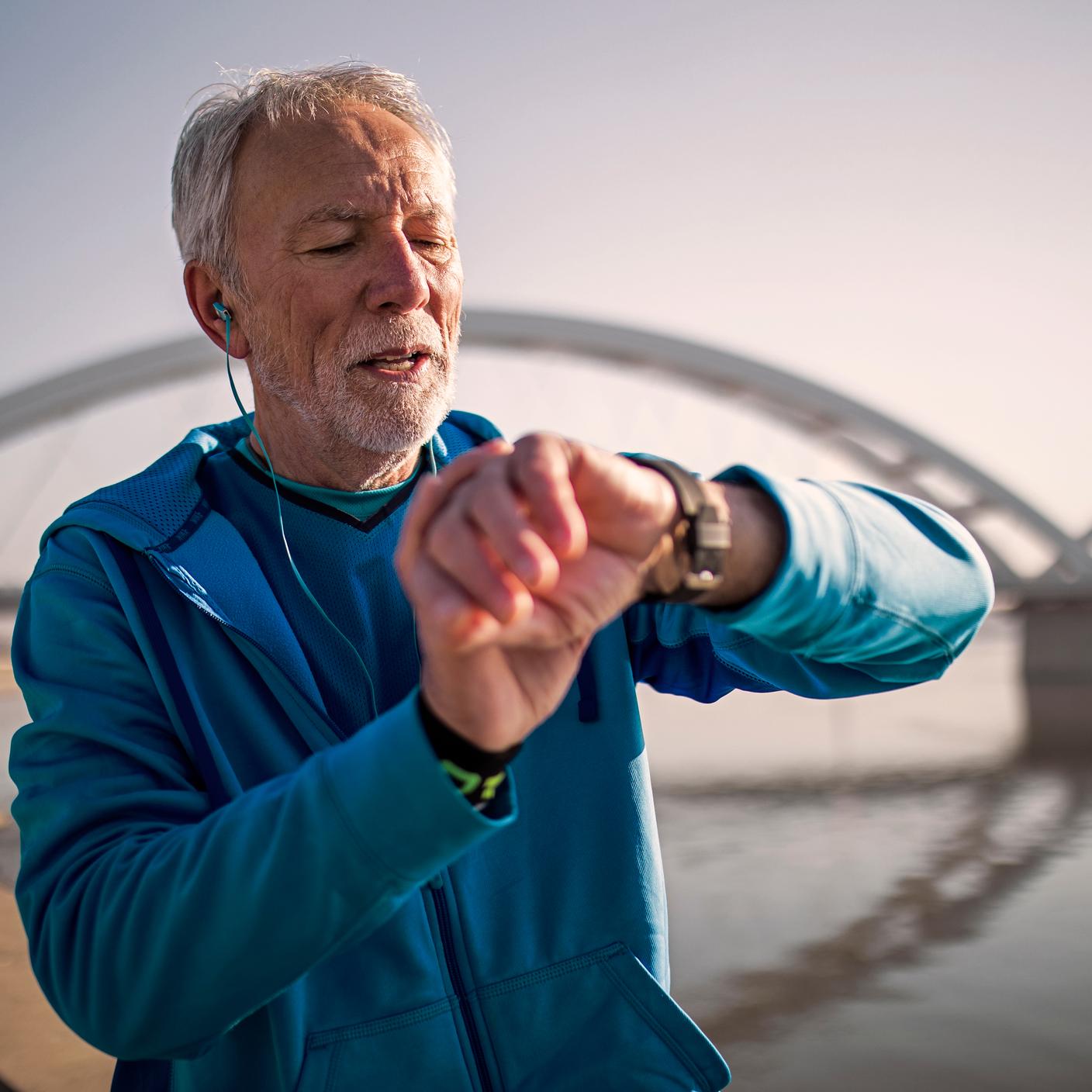 Male jogger on bridge checking smart watch