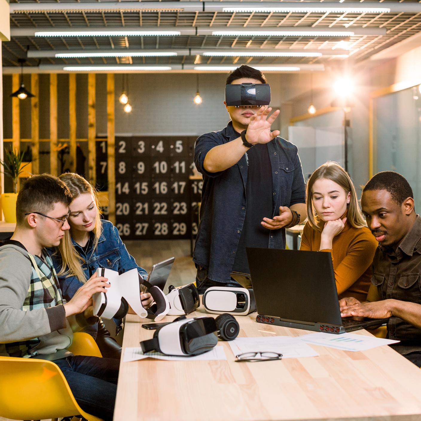 Team trying virtual reality glasses for work in creative office