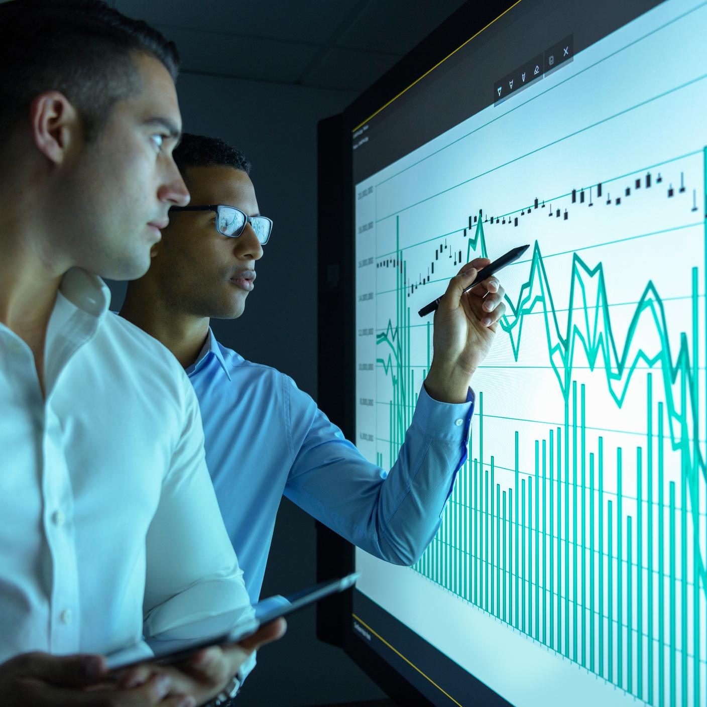 Businessmen studying graphs on an interactive screen in business meeting