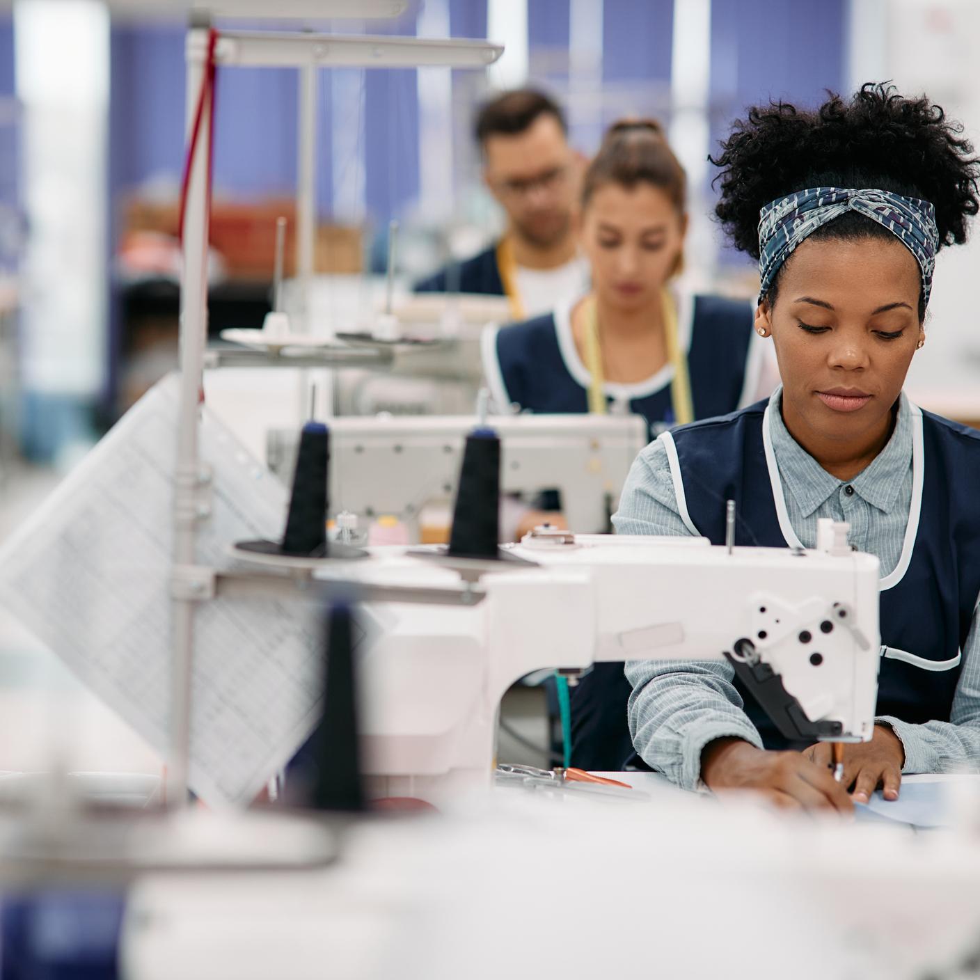 Woman sewing while working as seamstress at clothing factory