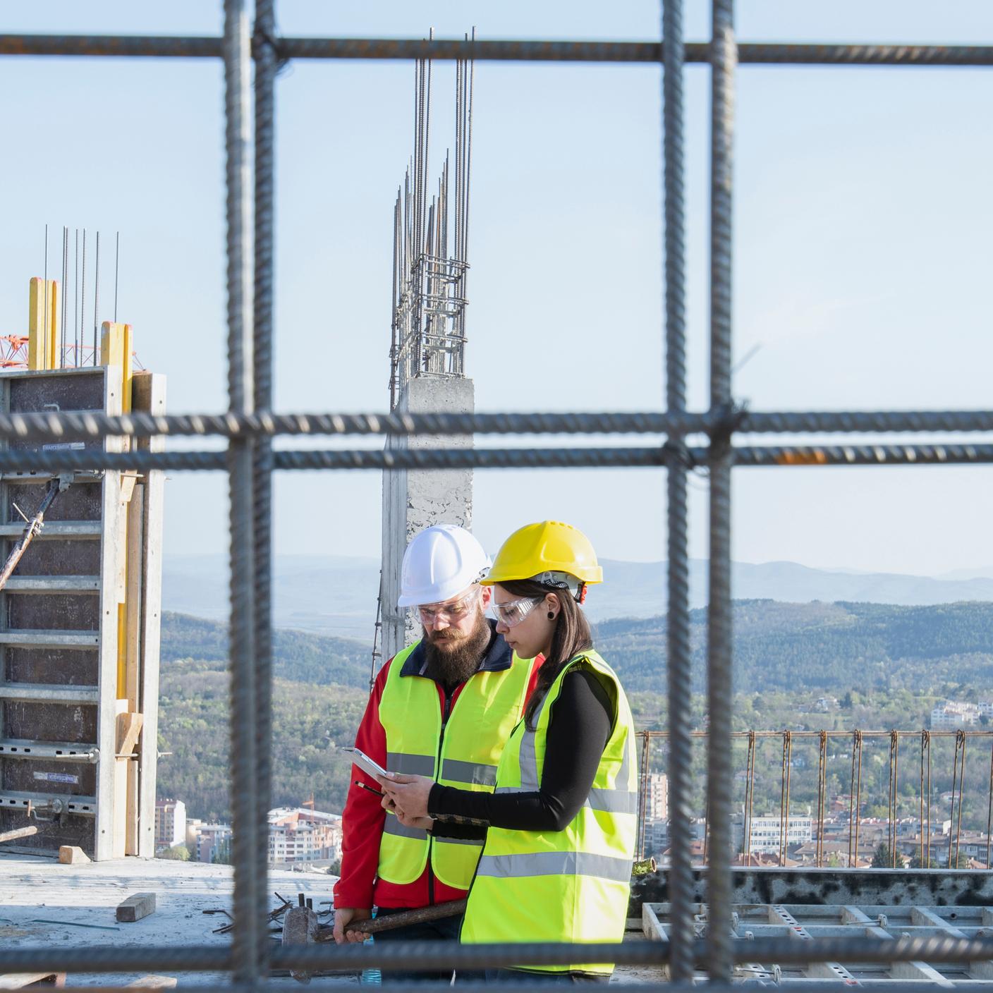 Construction workers standing on outdoor construction site discussing the building plans. 