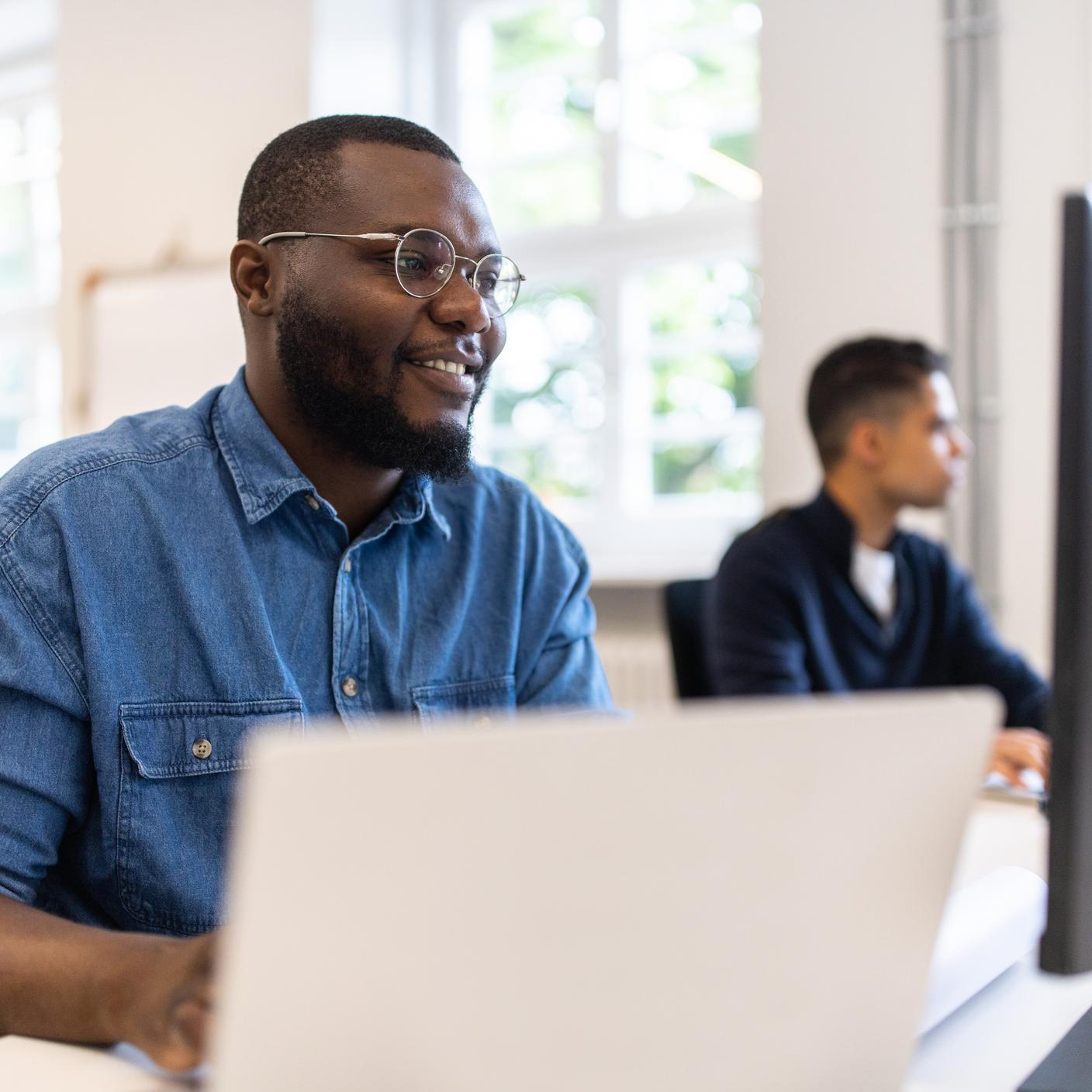 Telesoft Technologies made standards key to strategy - Happy African man working on desktop PC at a coworking office