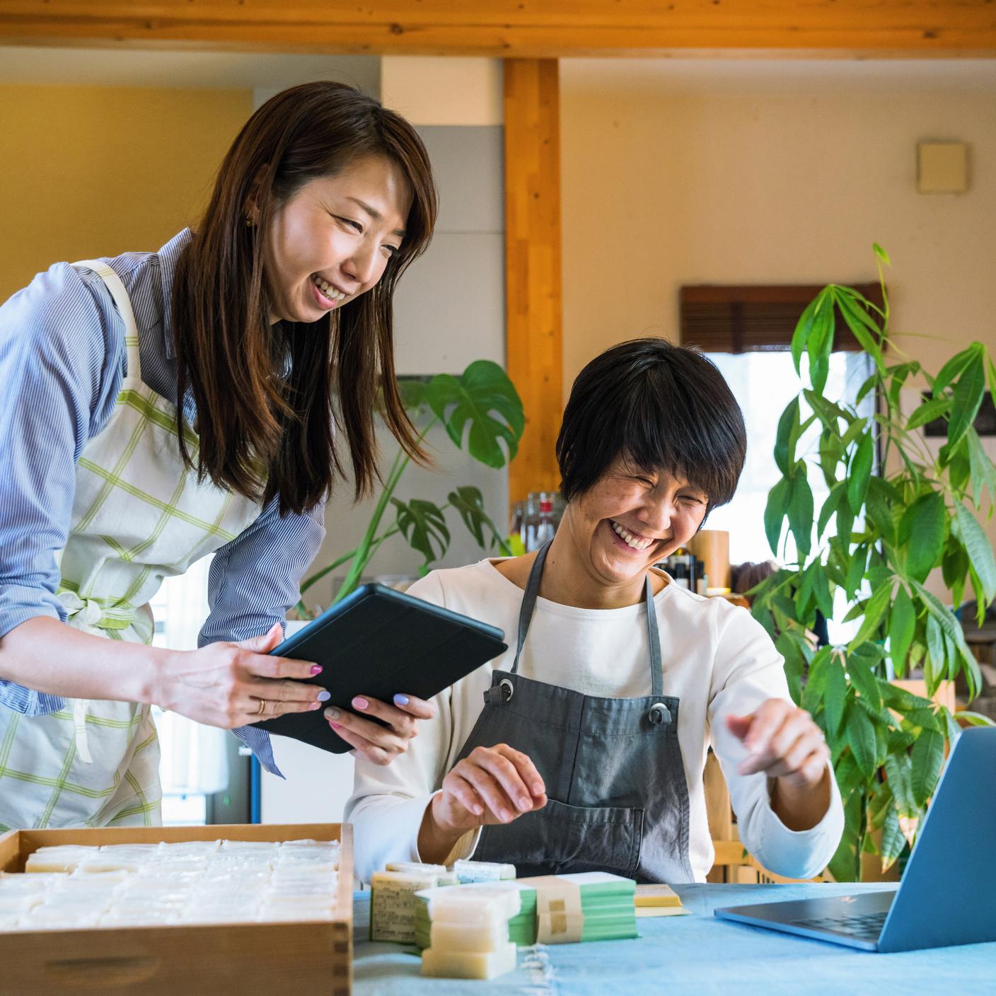 Two women selling organic soap and consulting their laptop