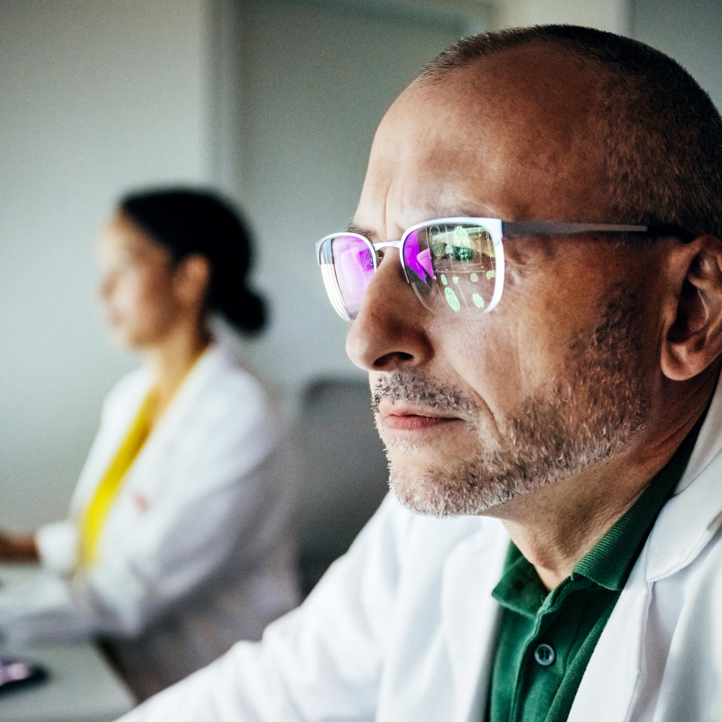 A man wearing glasses looking at his screen