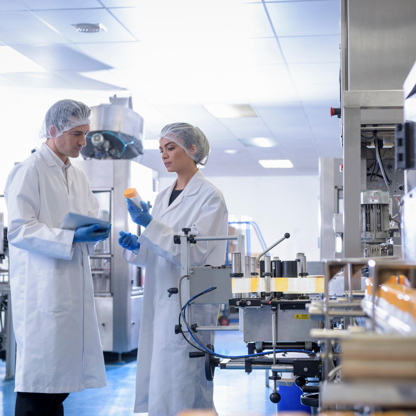 Workers inspecting product in pharmaceutical factory