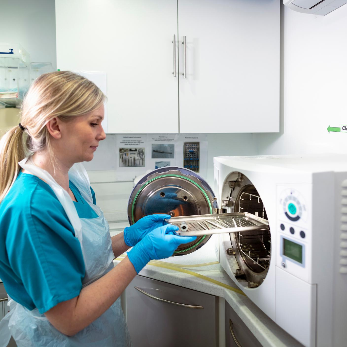 Dental nurse sterilizing dental equipment in dental surgery