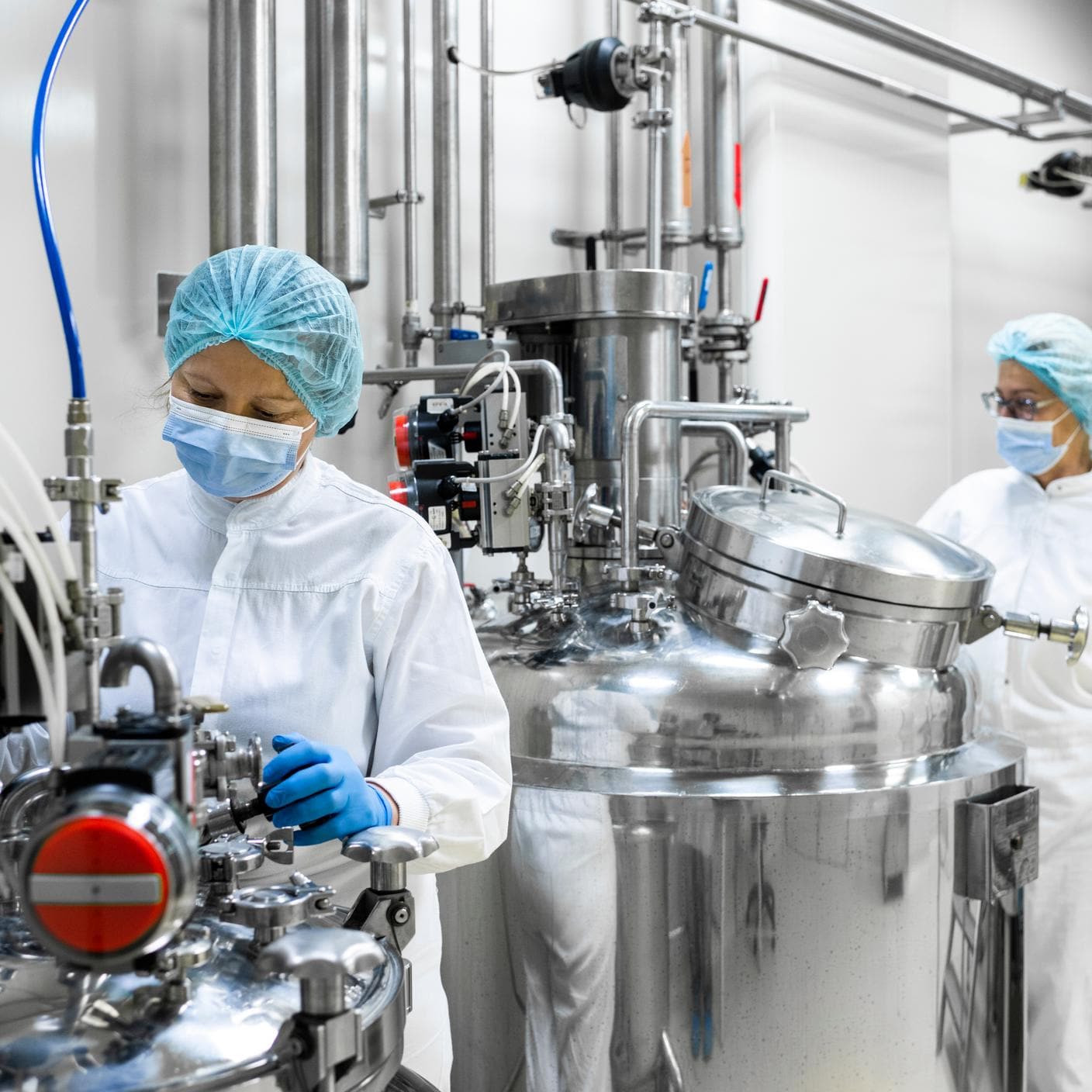 Is your PPE as diverse as your workforce - Two female employees in a laboratory wearing protective gloves, mask, cap and white suit