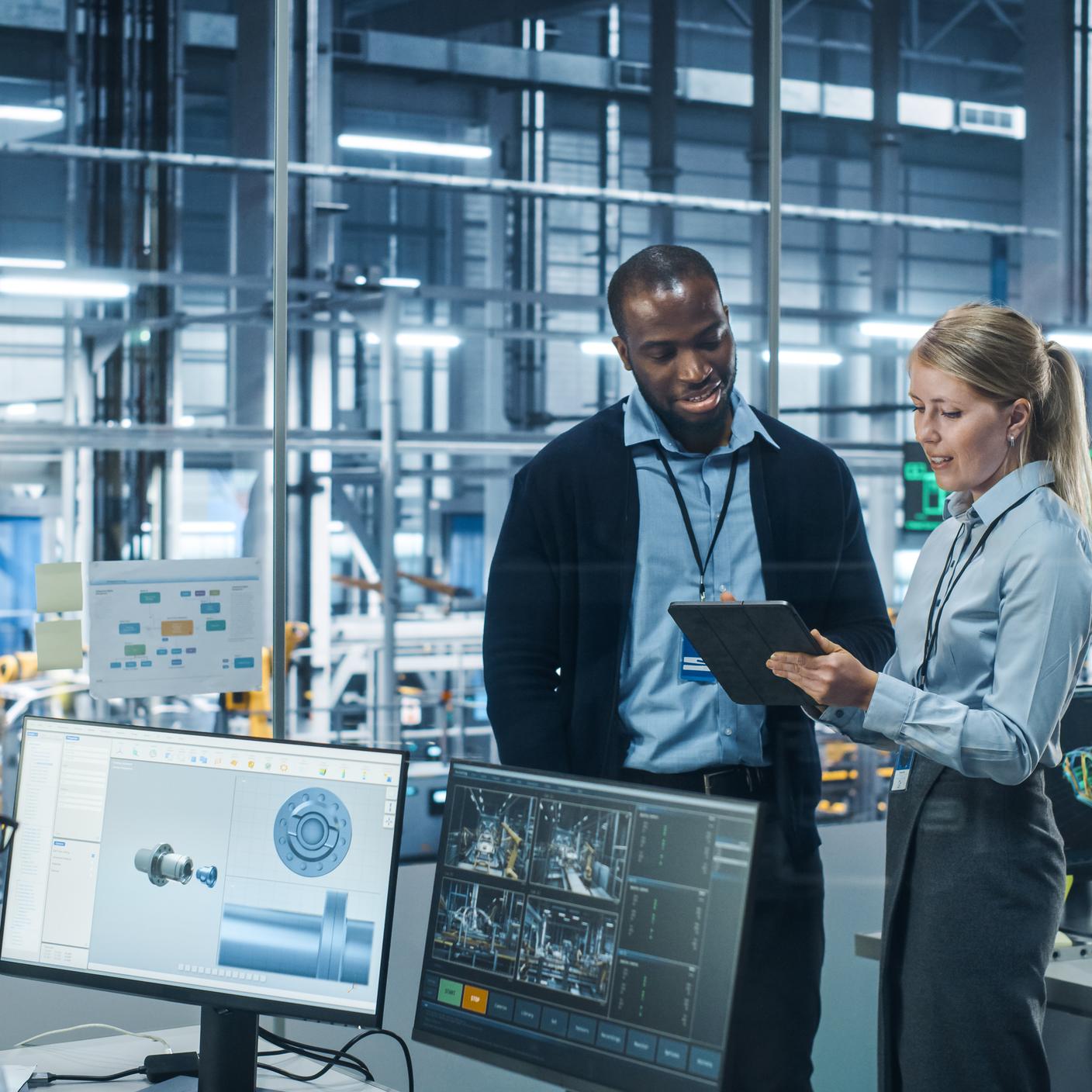 Car Factory Office: Female Engineer Talks with Male Scientist, Use Tablet Computer to Design Production Conveyor for Advanced Power Engines. Automated Robot Arm Assembly Line Manufacturing Vehicles