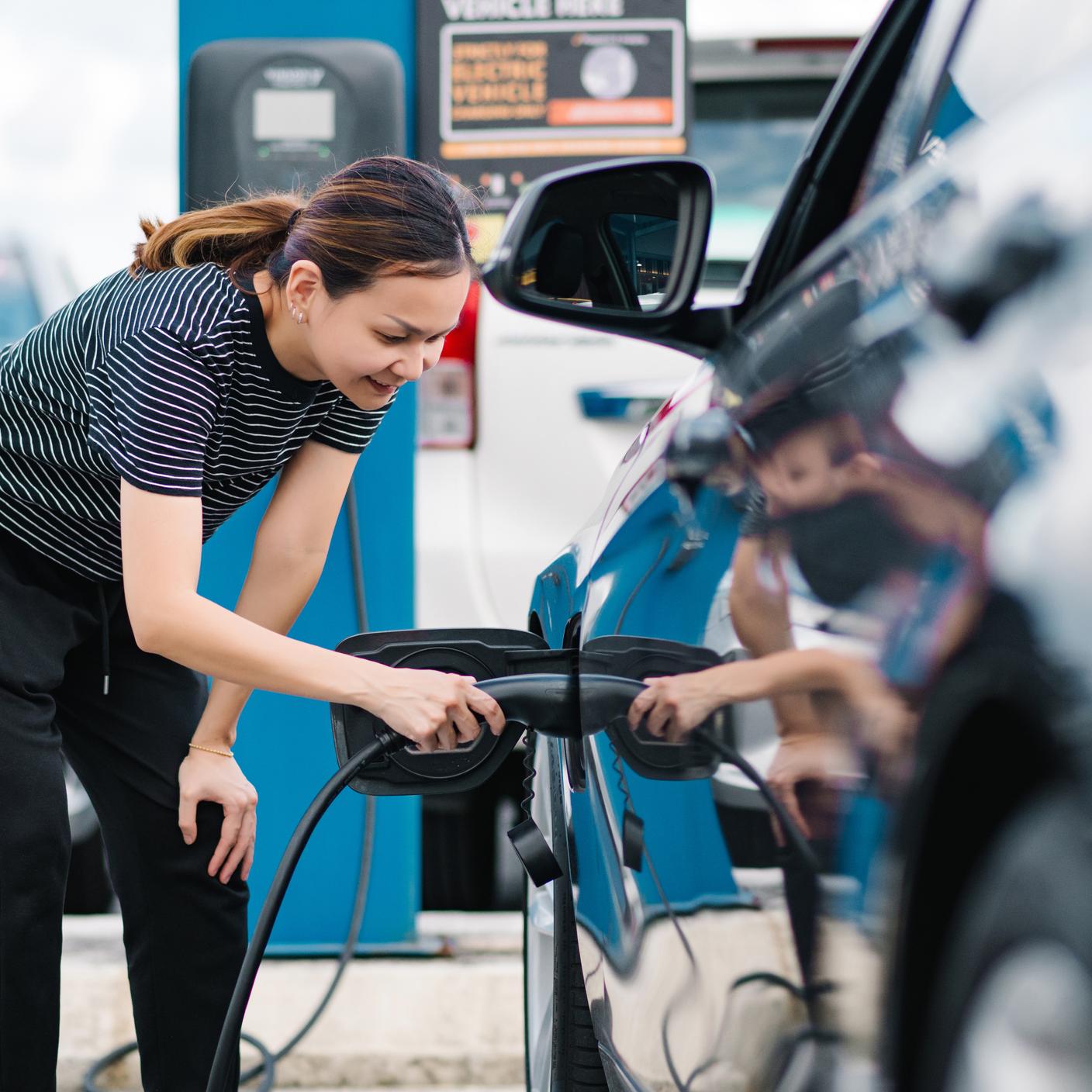 asian girl charging electric car