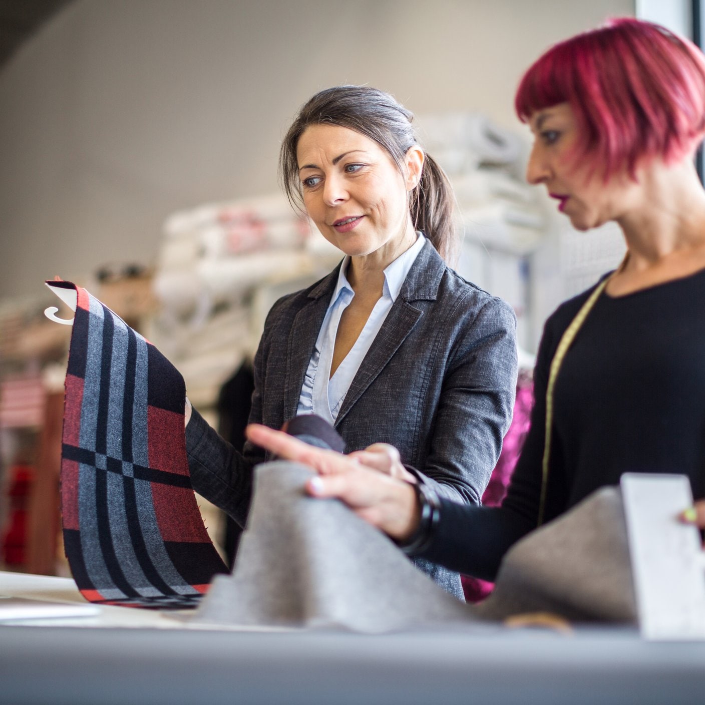 Female coworkers discussing over fabric at workshop