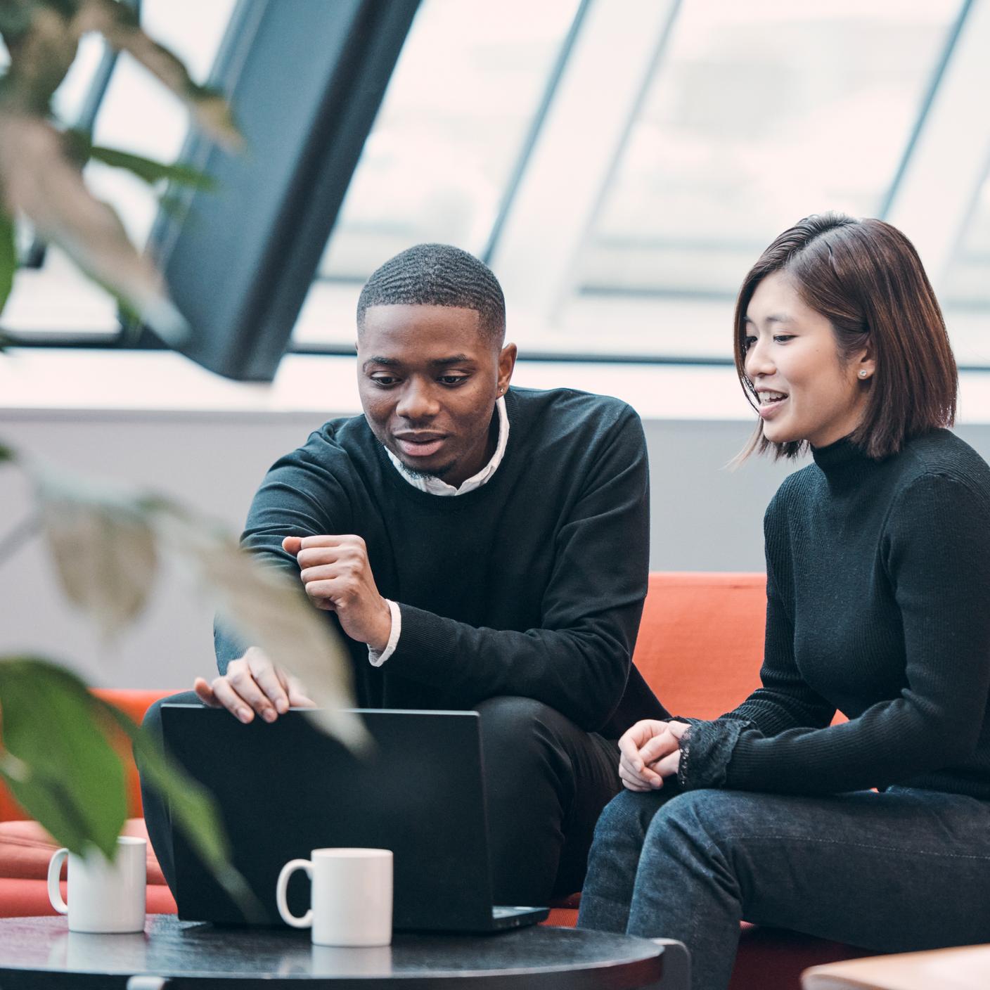 A man and a woman are consulting their laptop