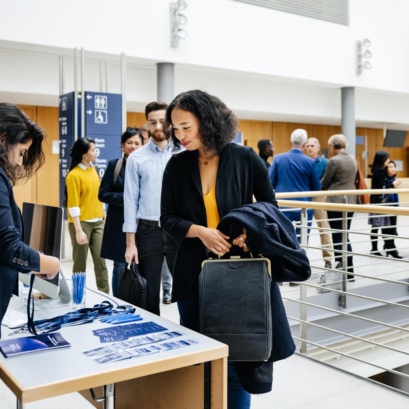 Some attendees queueing and signing in at a business conference registration desk