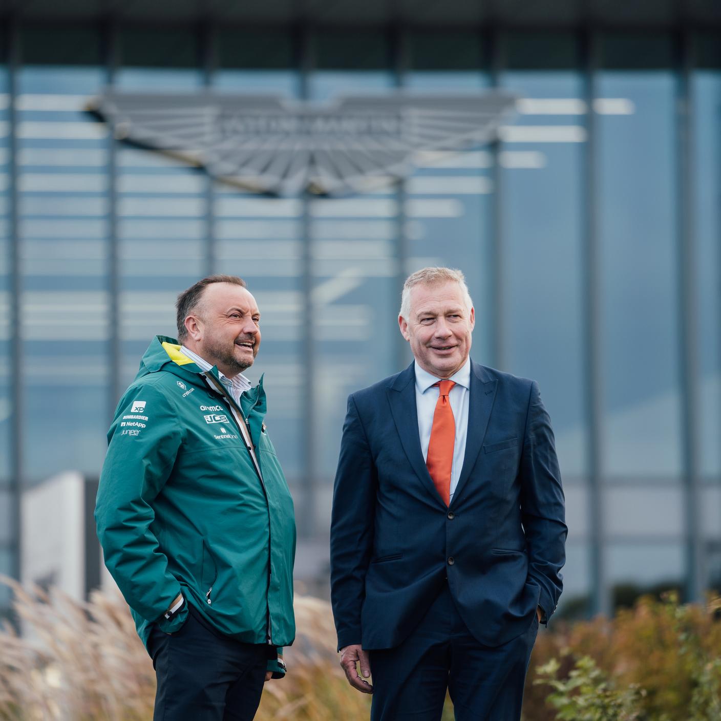 Client & BSI infront of Aston Martin logo on glass building