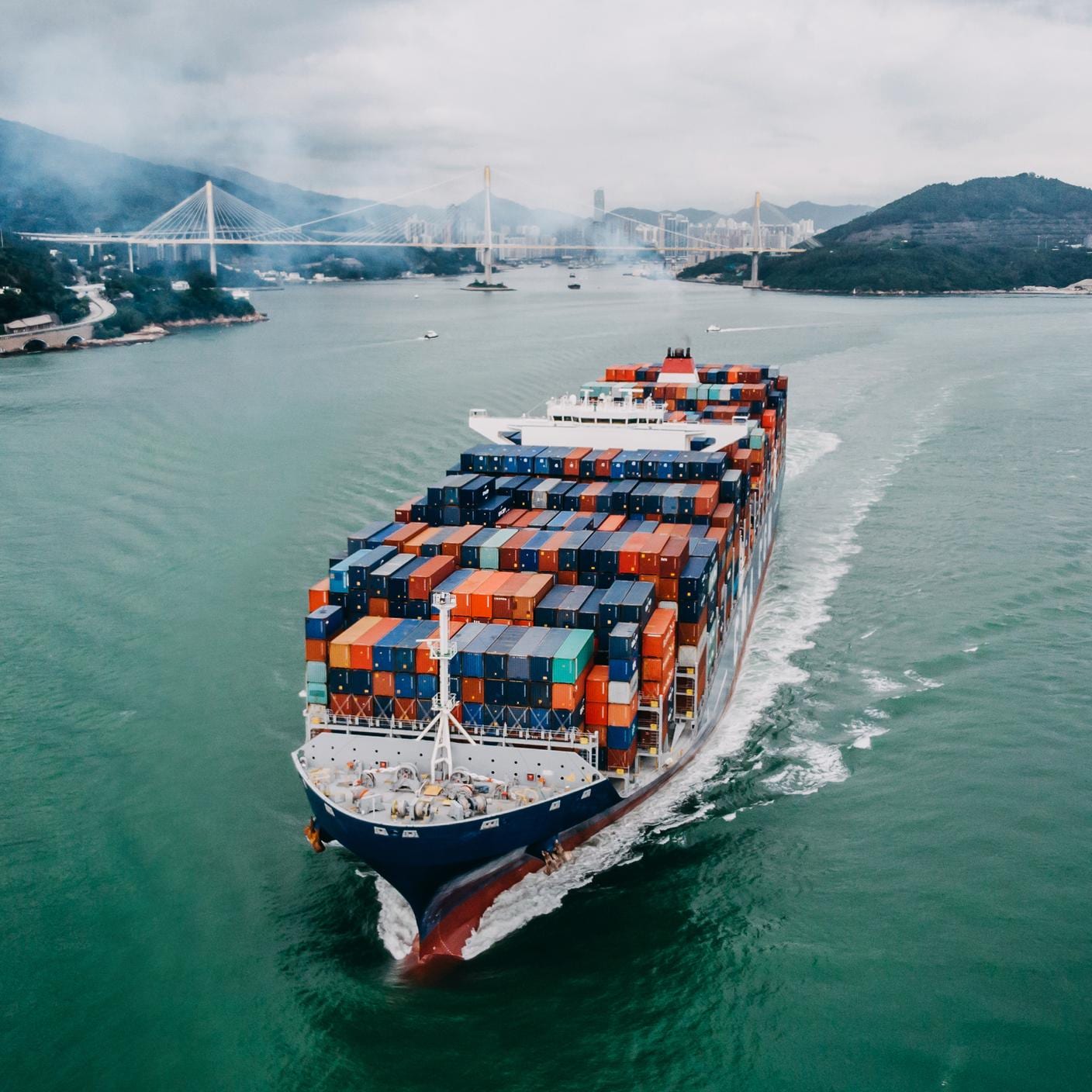 Aerial view of container ship transporting goods sailing across ocean leaving the port