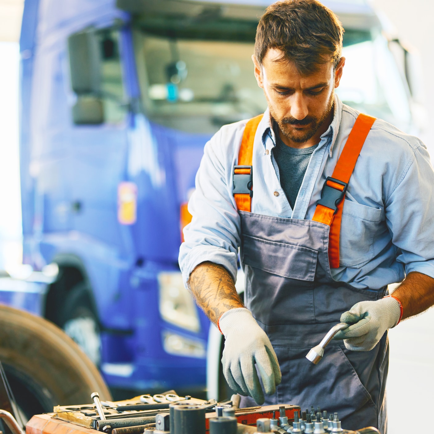 Truck repairing mechanic working with tools in a garage.