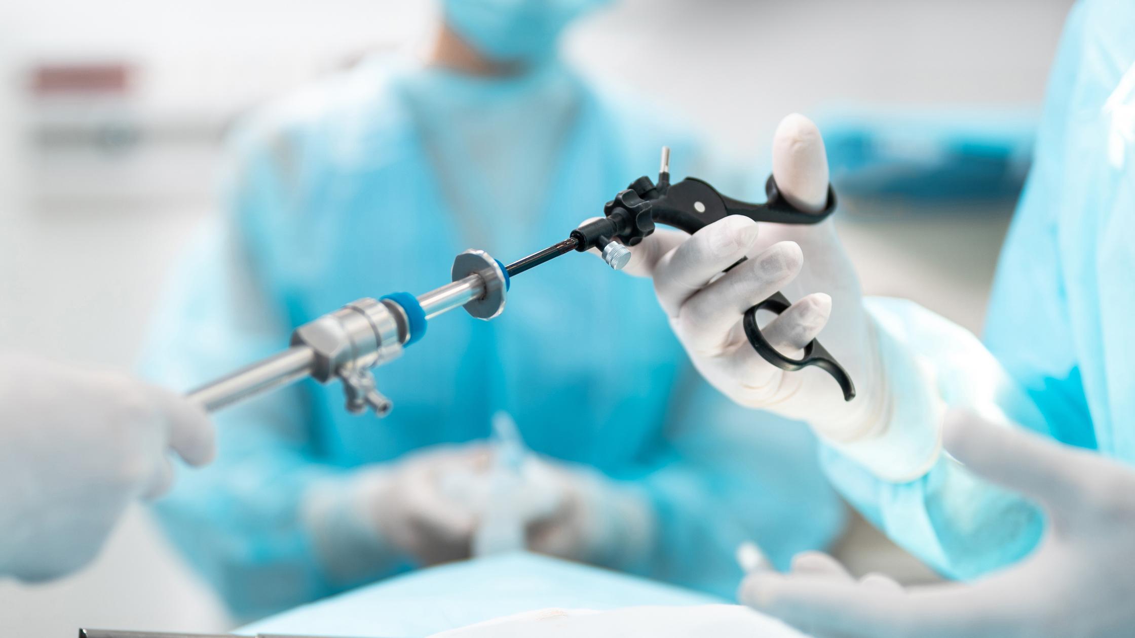 Close up of male and female hands holding laparoscopic grasper with trocar